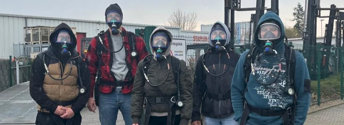 5 persons with breathing apparatus in front of a building